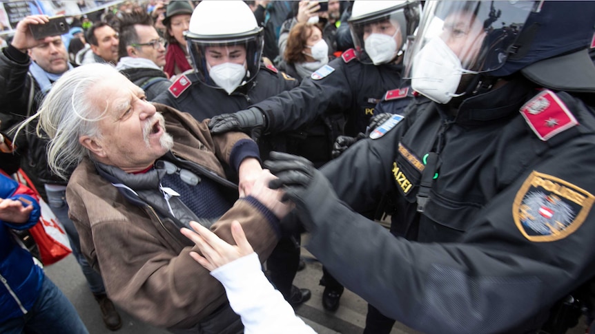 A protester debates with the police during a demonstration against COVID-19 restrictions in Vienna, Austria.