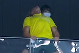 Dean Boxall is seen holding onto the stadium barriers and thrusting his head up in the air at the Tokyo Aquatics Centre.