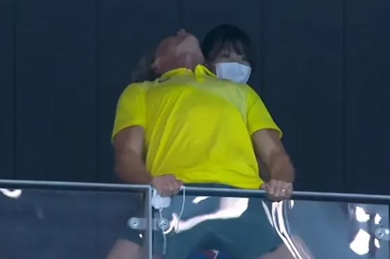 Dean Boxhall is seen holding onto the stadium barriers and thrusting his head up in the air at the Tokyo Aquatics Centre.