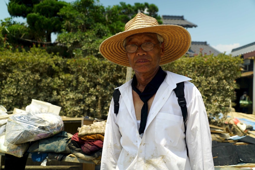 Koichi Kawata poses for a photo with rubbish piled up behind him.