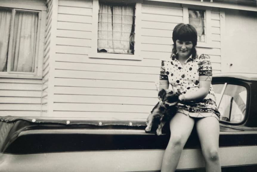 A woman sitting on a car.