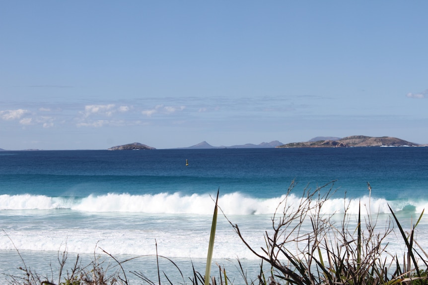 Waves crash on the shoreline, a yellow beacon floats a few hundred metres away.