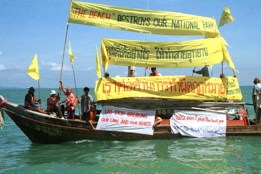Thai environmentalists display banners aboard a boat during a protest