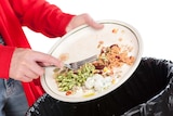 Scraping a plate with food into the bin