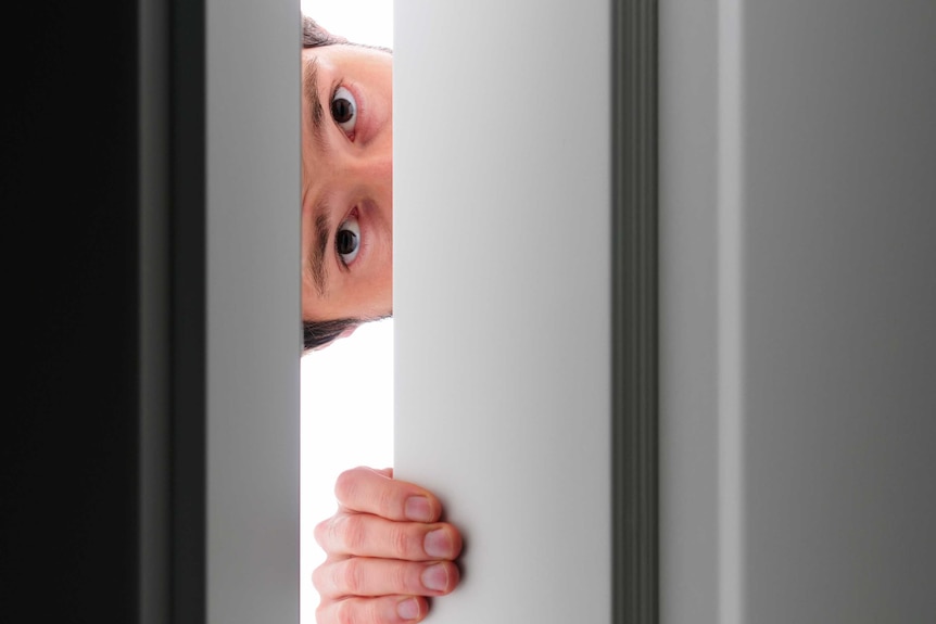 Autism - boy hides behind a door