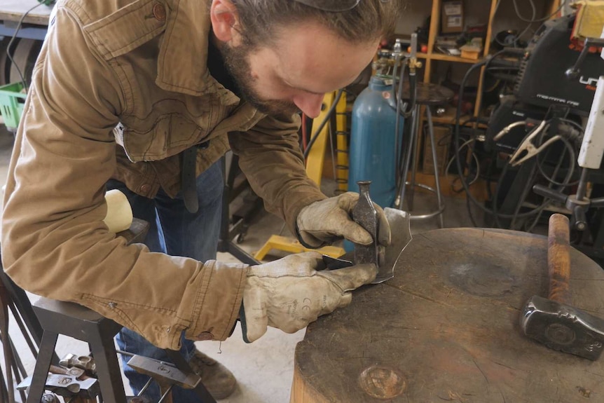 A man doing metal work in a studio.