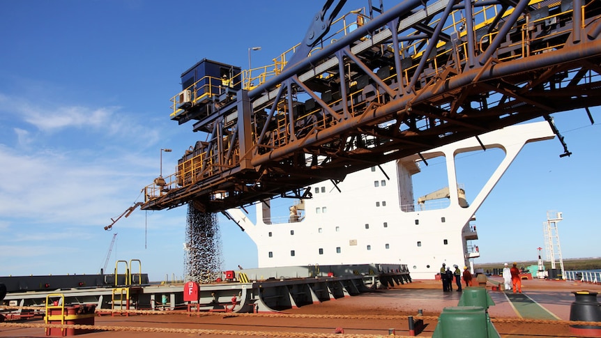 A horizontal crane pumps ore into the hold of a ship