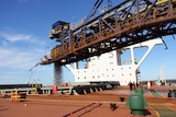 Horizontal crane pumping iron ore into ship in Pilbara