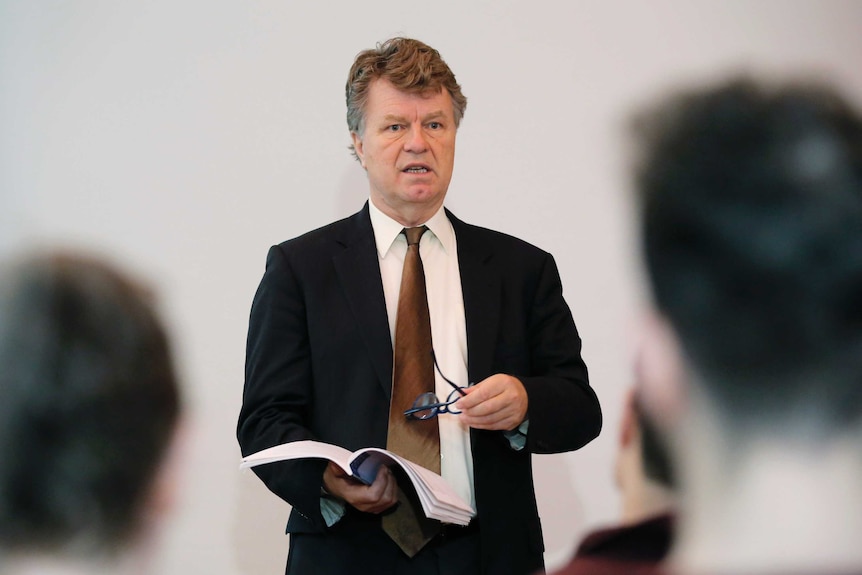 Boris Dittrich speaking at a news conference while holding the report.