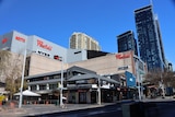 Exterior of a Westfield shopping centre with apartments behind on a sunny day.