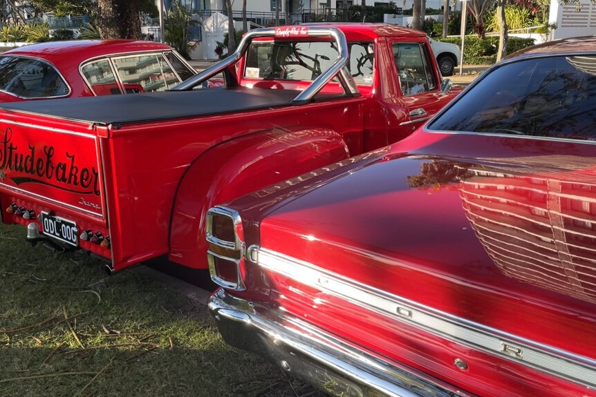 Three red vintage cars lined up next to each other