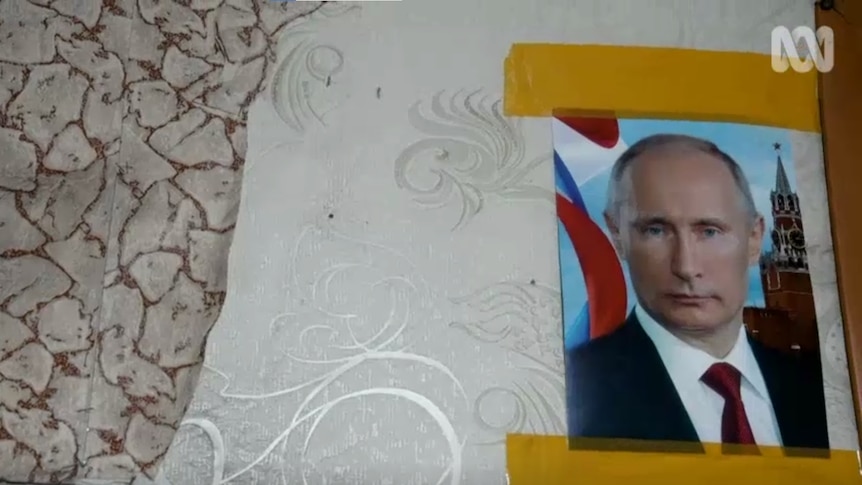A screenshot shows a photo of Putin taped to a wall.