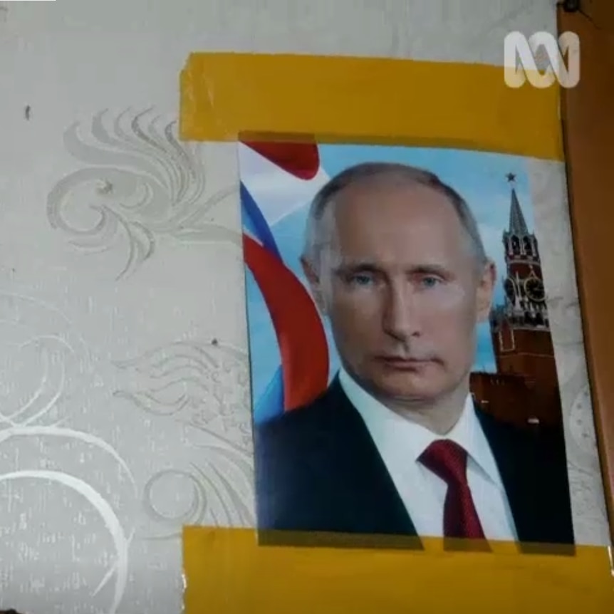 A screenshot shows a photo of Putin taped to a wall.