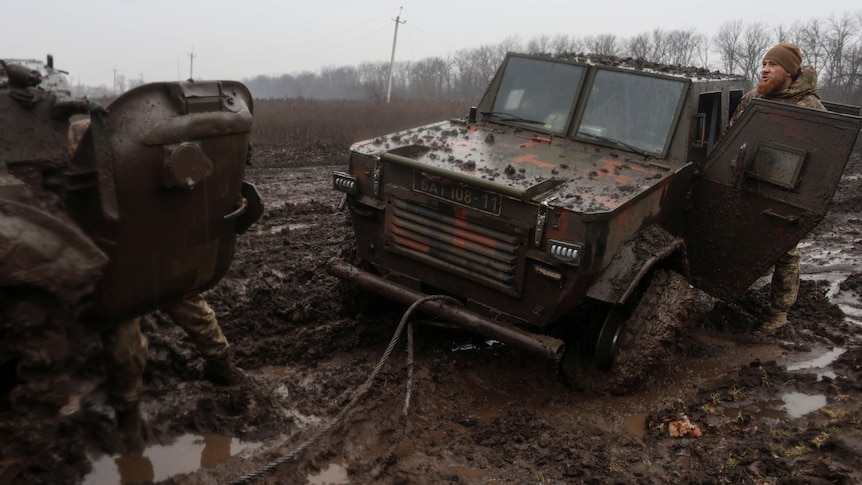 Soldiers attempt to tow a vehicle stuck in mud
