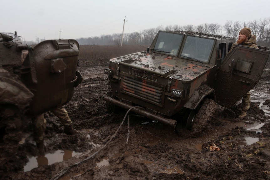 Soldiers attempt to tow a vehicle stuck in mud