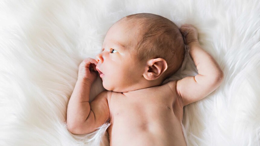 A baby lies on its back on a furry white blanket, for a story on sperm donation.