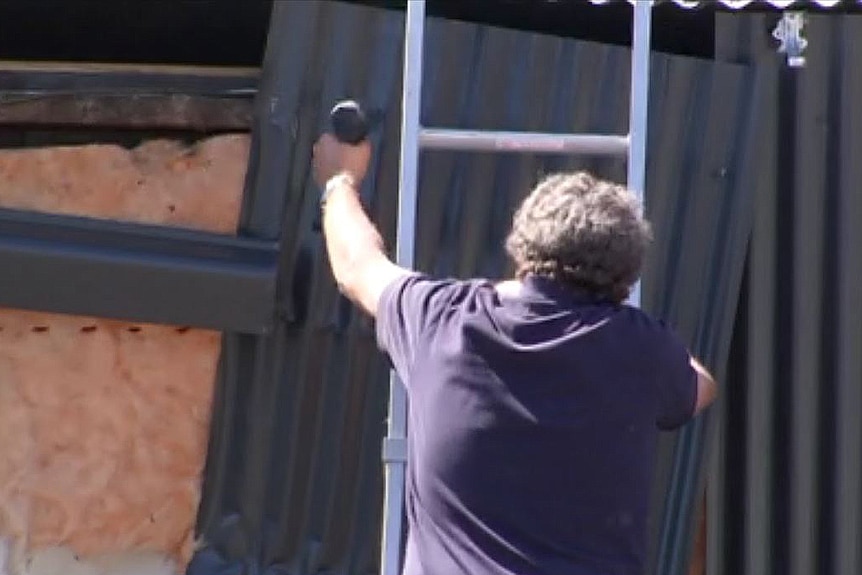 Man repairing damage to Outlaws clubhouse caused by police raid, Hobart, December 22, 2016.