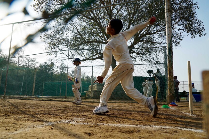 A junior cricketer bowls in the nets in Delhi