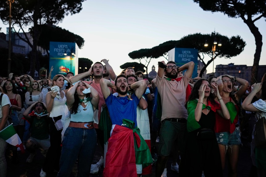 Un grupo de hinchas de fútbol italianos se llevan las manos a la cabeza desesperados después de jugar la Eurocopa 2020.