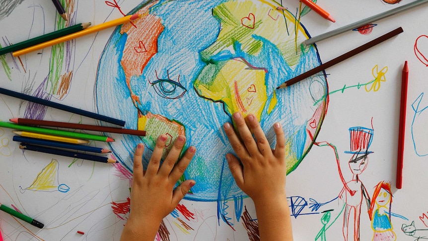 A child drawing with colour pencils a picture of Earth.