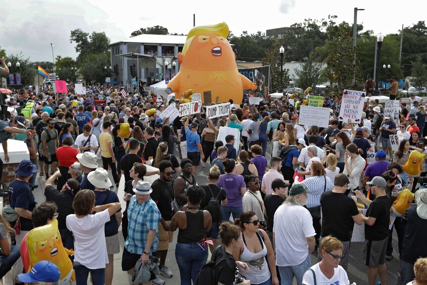 An inflatable Baby Trump balloon towers over protesters during a rally.