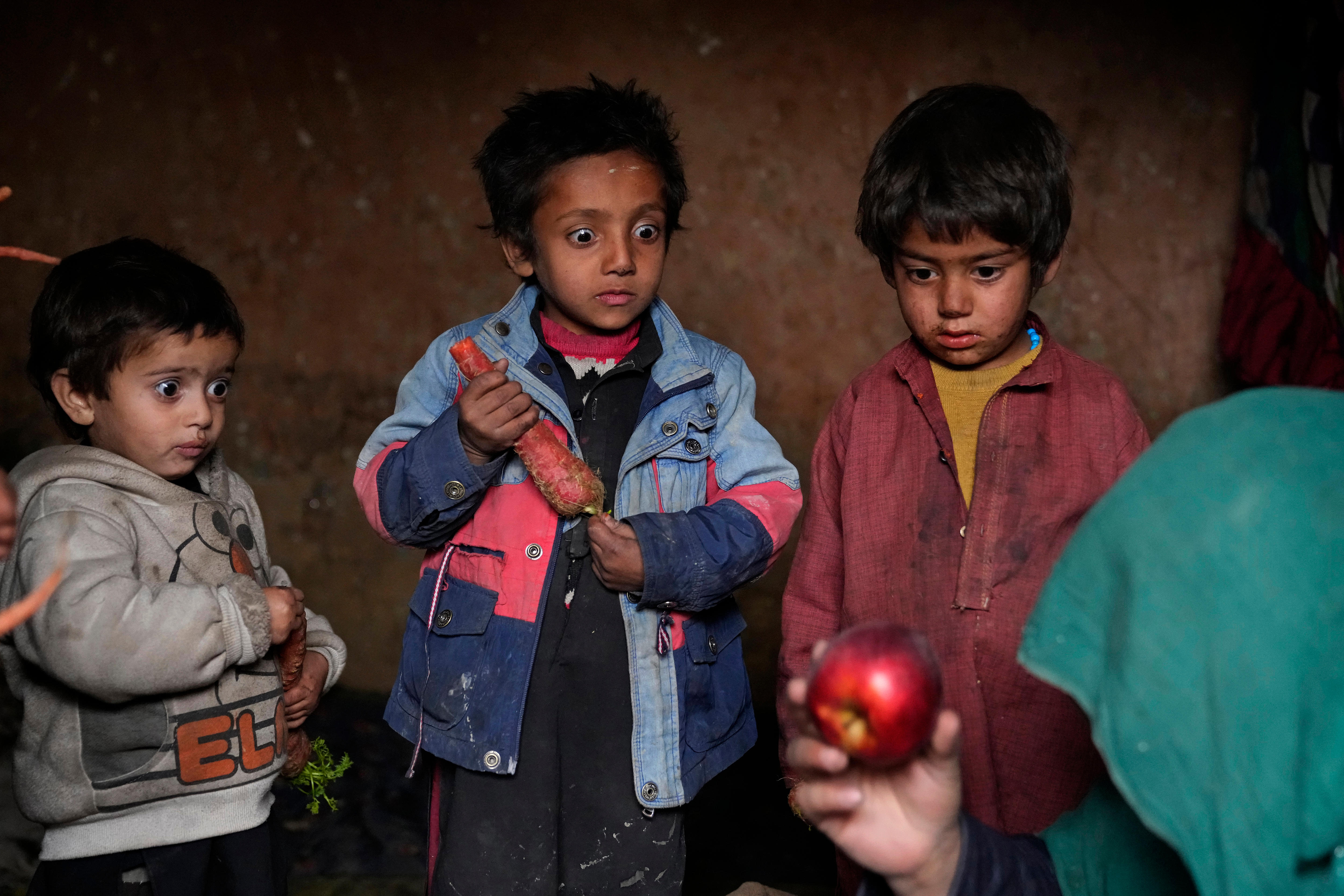 Three small children stare almost transfixed on a red apple