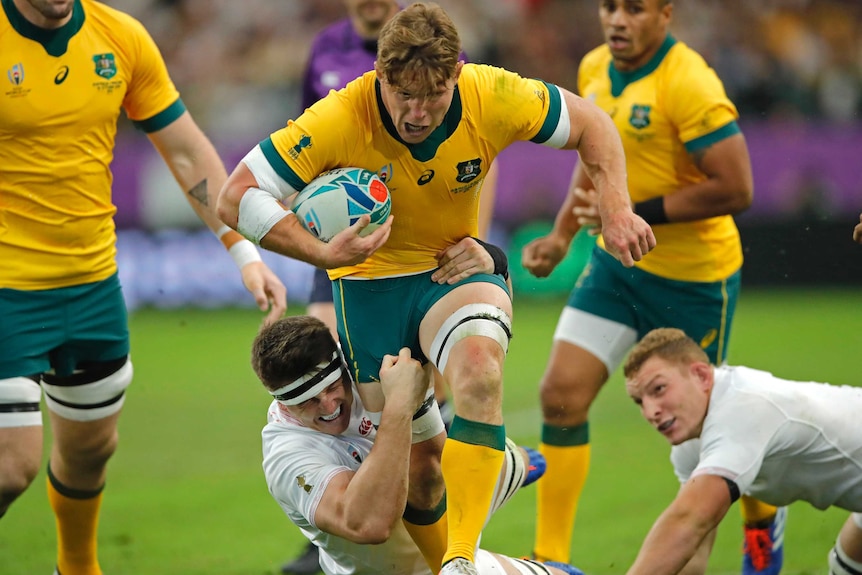 A Wallabies player holds the ball as he is tackled by an England player at the Rugby World Cup.