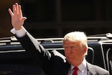 Donald Trump waves while standing next to his car.
