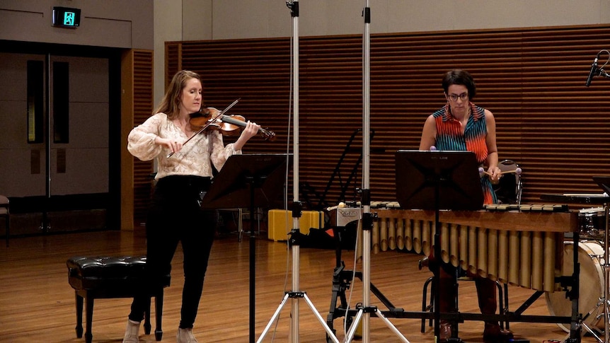Two musicians in a recording studio playing violin and vibraphone.
