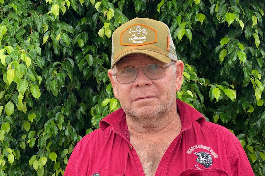 A man in a red shirt and a baseball cap.