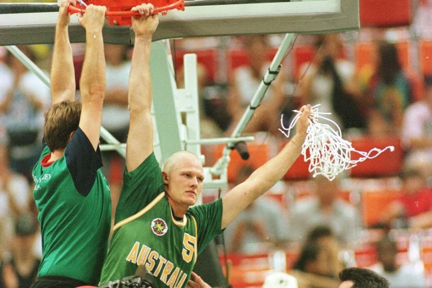 Two Australian male wheelchair basketball players hang from the ring as they celebrate winning gold at the 1996 Paralympics.