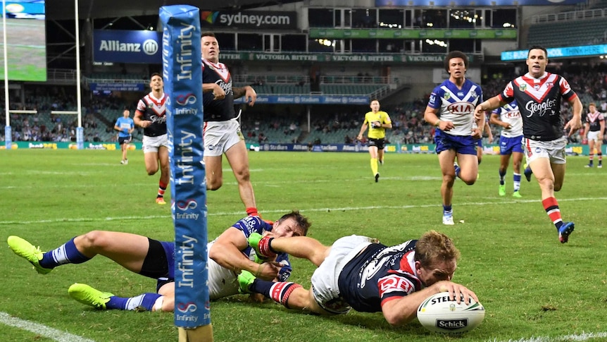 Mitchell Aubusson (centre) of the Roosters scores a try.