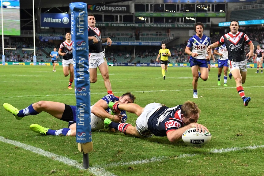 Mitchell Aubusson (centre) of the Roosters scores a try.