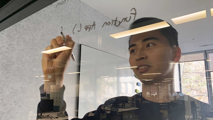 A man writes on a window in a black marker.