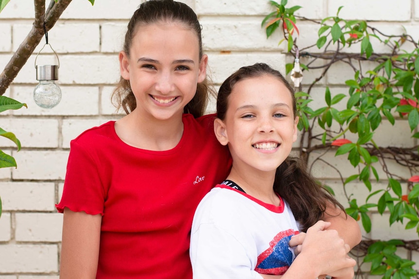 Sisters Ruby and Isobel Donaldson smile, Ruby has an arm around Isobel.