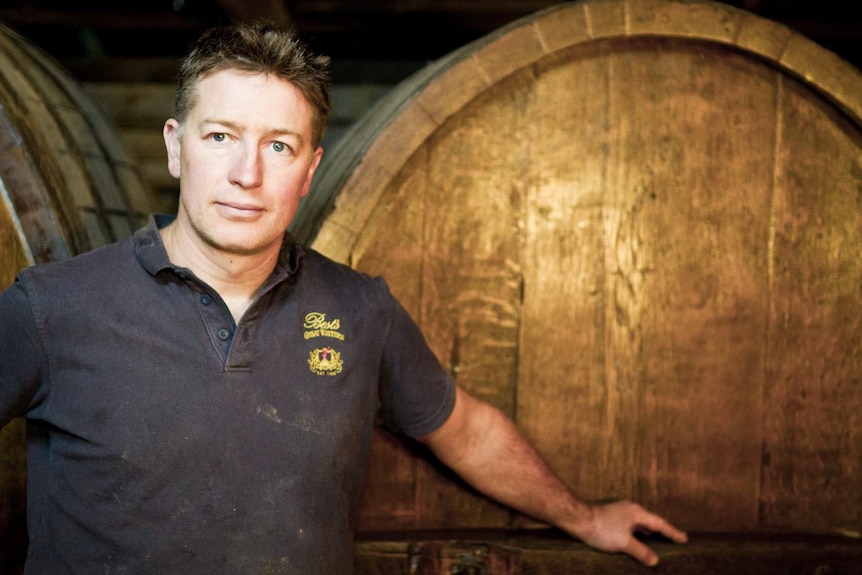 Justin Purser standing in front of a wine barrel