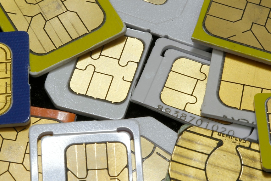 A close up of a pile of SIM cards lying on a table, overlapping and showing their metal contacts