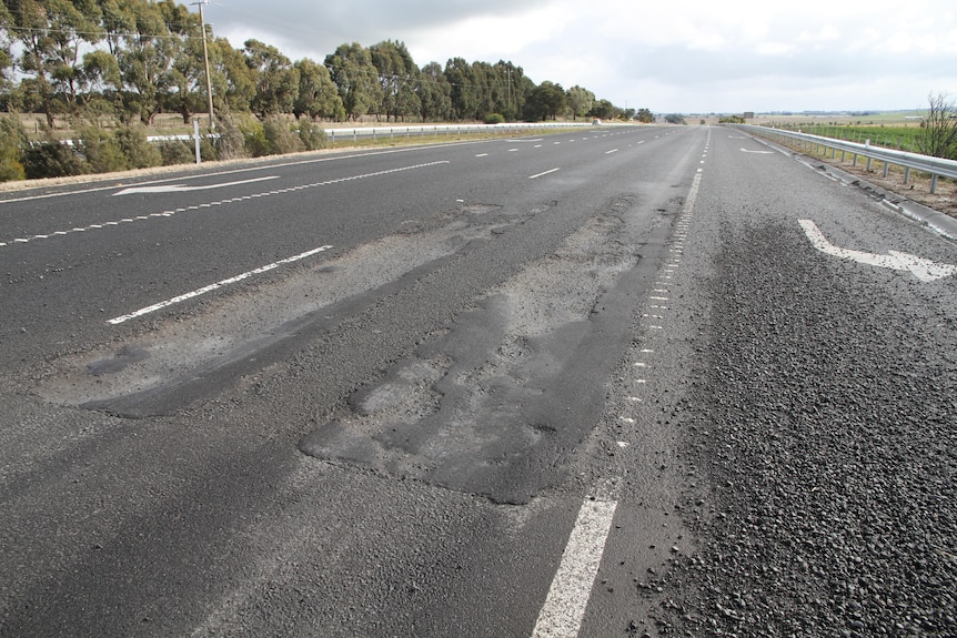 Close up photo of two big potholes on a freeway.