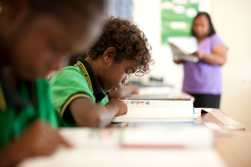 Children read from a book in a classroom.