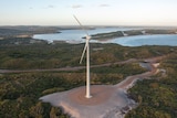 An aerial photo of a wind turbine with a coastal scene in the background