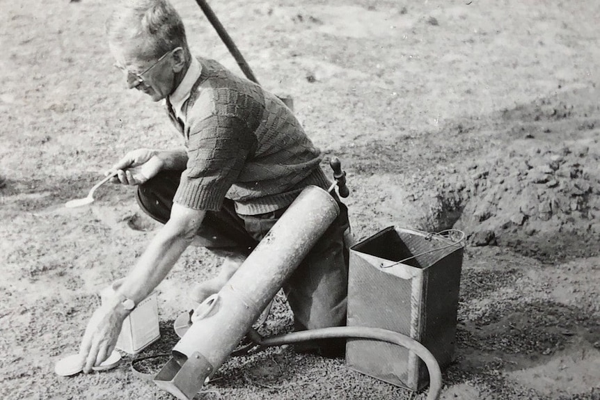 A black and white image of a farmer laying poison baits for rabbits.