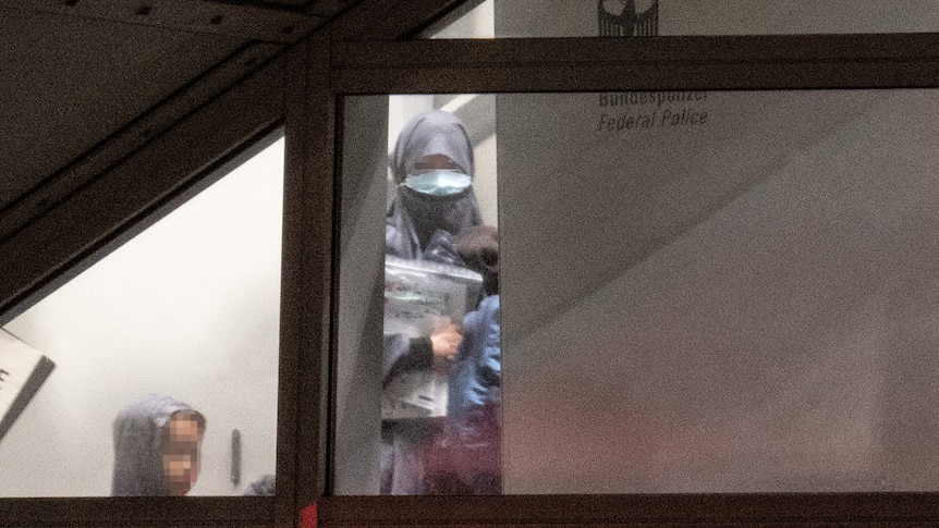 A woman and child with faces blurred out seen through an airport window.