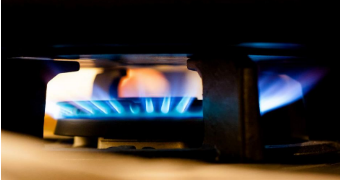Gas flame burns on stove, close up.