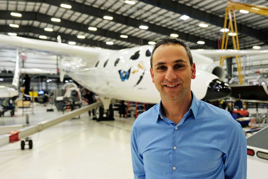 Enrico Palermo stands in front of a hangar full of spaceships