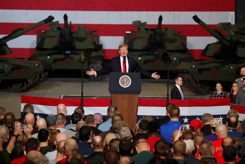 Donald Trump speaks to workers in front of US Army tanks.