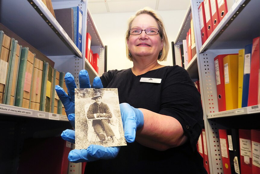 Australian War Memorial curator Joanne Smedley holds a sepia photograph of WWI soldier with no hands, gripping a pen.