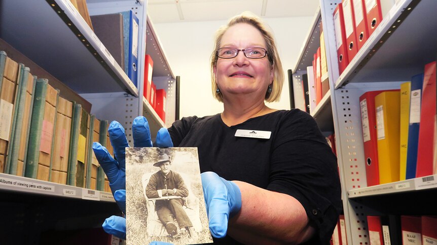 Australian War Memorial curator Joanne Smedley holds a sepia photograph of WWI soldier with no hands, gripping a pen.