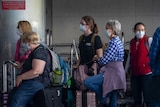 A queue of people wearing face masks queues at an airport in Guatemala City