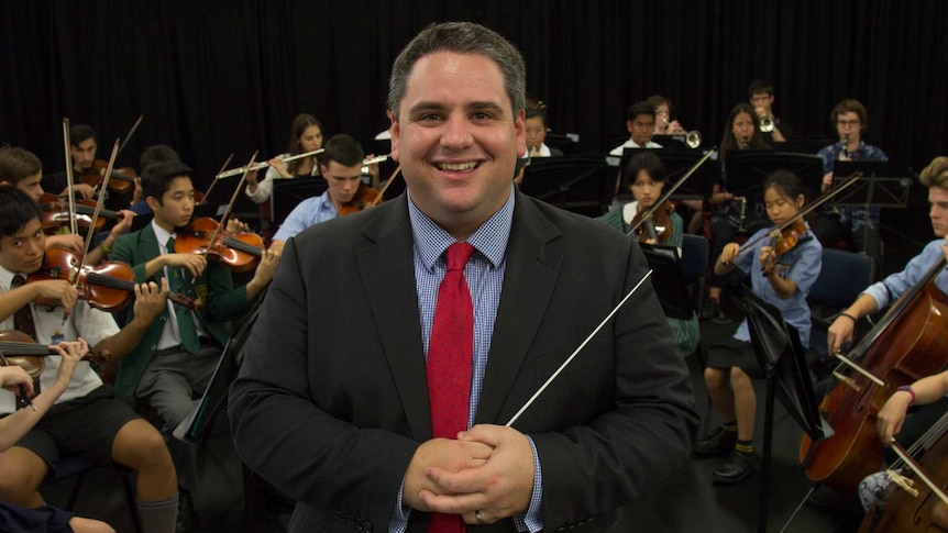 James Pensini stands in front of the Western Sydney Youth Orchestra