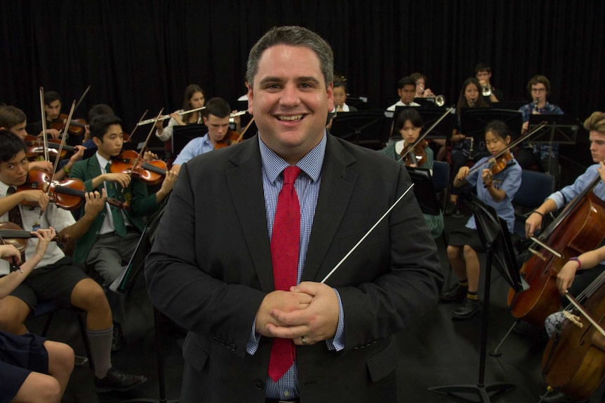 James Pensini stands in front of the Western Sydney Youth Orchestra